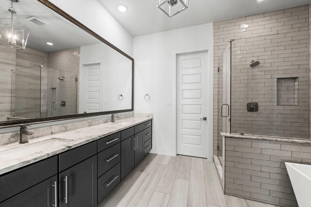 bathroom with vanity, separate shower and tub, and a notable chandelier