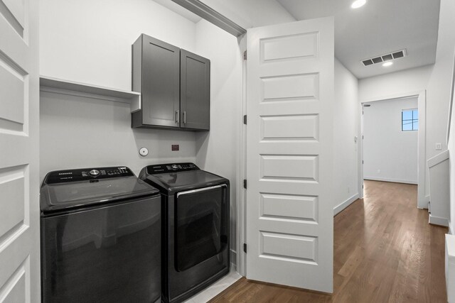 laundry area featuring cabinets, dark wood-type flooring, and washing machine and clothes dryer