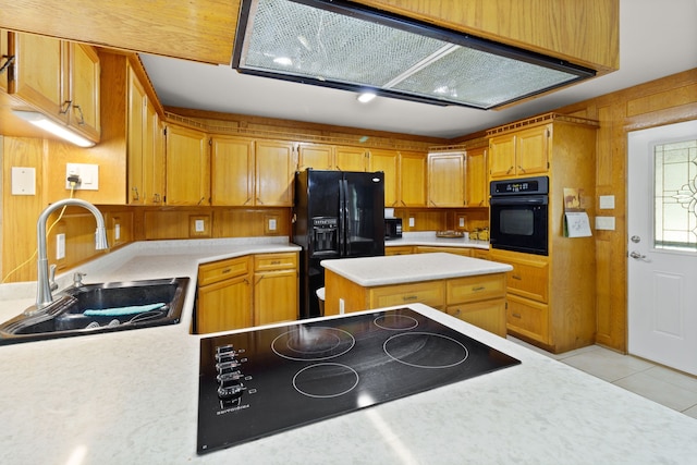 kitchen featuring sink, light tile patterned floors, wooden walls, a kitchen island, and black appliances