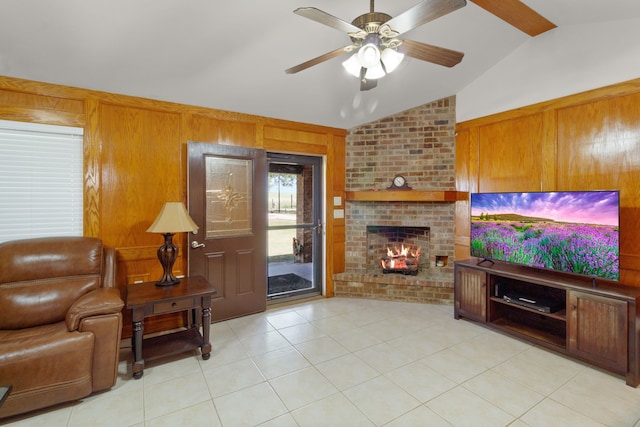 tiled living room with a brick fireplace, brick wall, ceiling fan, wooden walls, and lofted ceiling