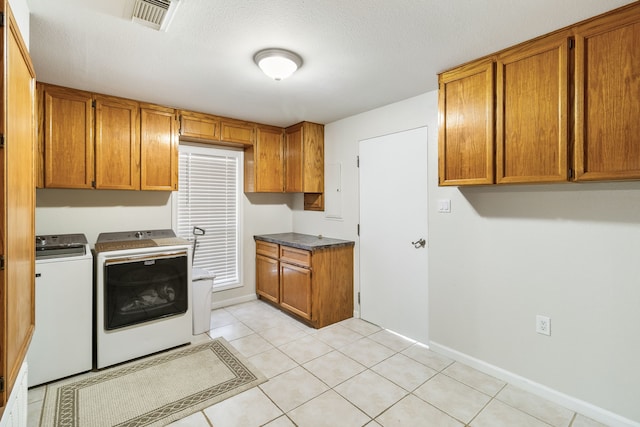 kitchen with light tile patterned floors, a textured ceiling, and washing machine and clothes dryer