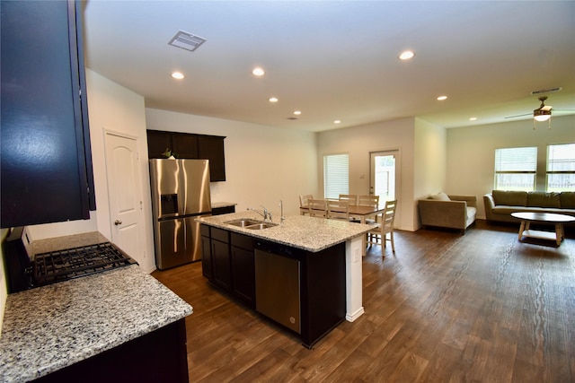 kitchen featuring light stone countertops, a center island with sink, dark hardwood / wood-style flooring, appliances with stainless steel finishes, and sink