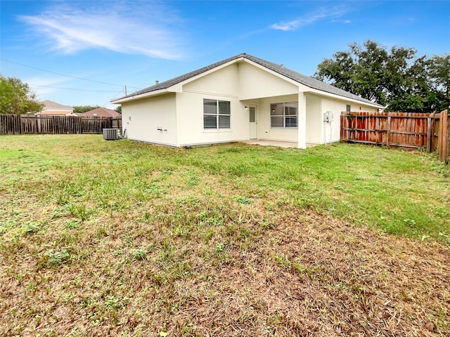 rear view of property with central AC and a yard