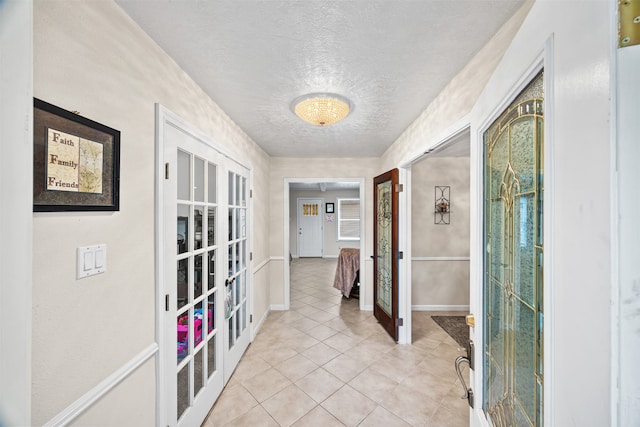 hall featuring french doors, light tile patterned floors, and a textured ceiling