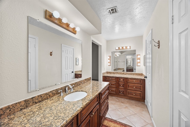 bathroom featuring tile patterned flooring, vanity, and a textured ceiling