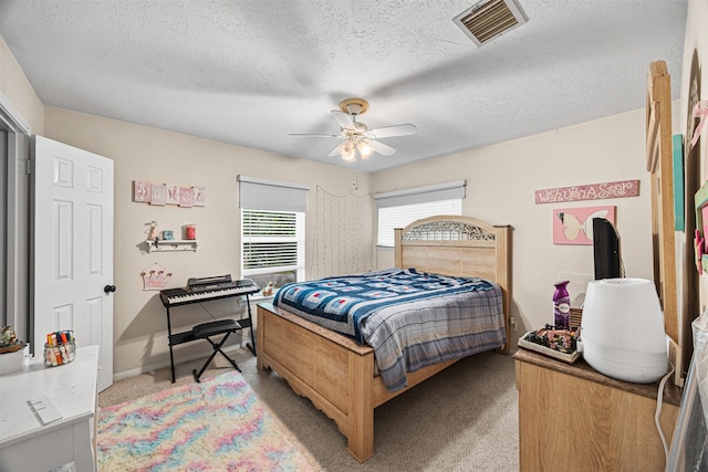 bedroom featuring ceiling fan, light colored carpet, and a textured ceiling