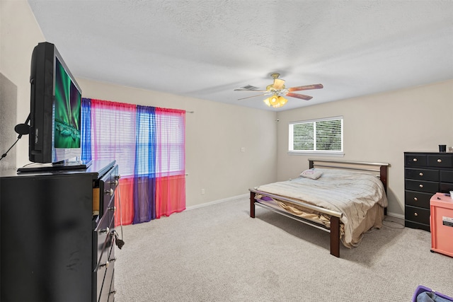 bedroom with ceiling fan, light colored carpet, and a textured ceiling