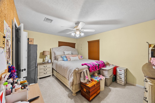 bedroom with a textured ceiling, ceiling fan, and light carpet