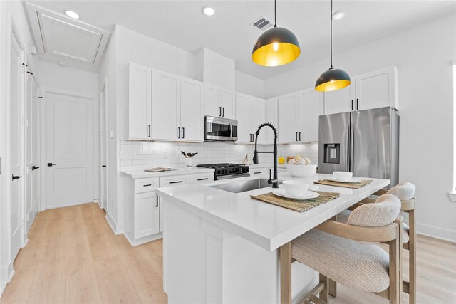 3109 Jensen Dr Unit B, Houston, TX 77026 - kitchen with decorative light fixtures, light hardwood / wood-style floors, white cabinetry, and stainless steel appliances