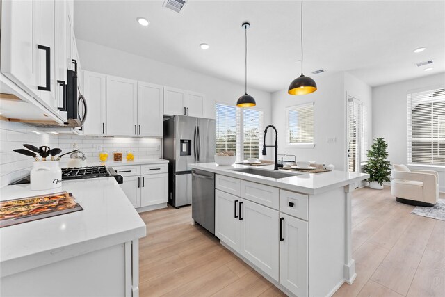 3109 Jensen Dr Unit B, Houston, TX 77026 - kitchen featuring pendant lighting, a kitchen island with sink, white cabinets, sink, and appliances with stainless steel finishes