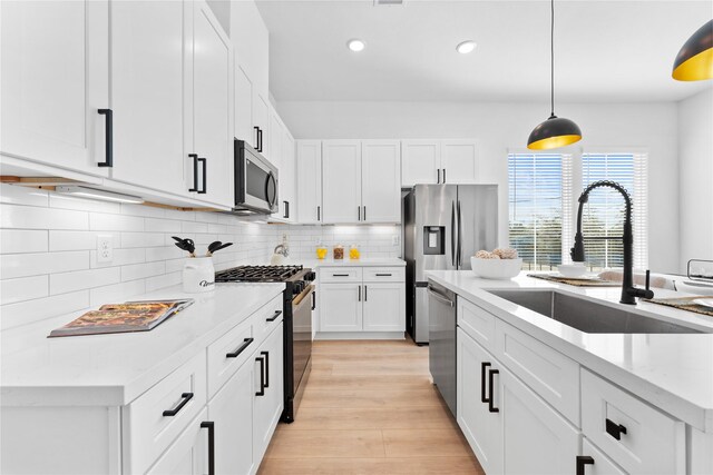 3109 Jensen Dr Unit B, Houston, TX 77026 - kitchen with appliances with stainless steel finishes, light wood-type flooring, sink, white cabinets, and hanging light fixtures