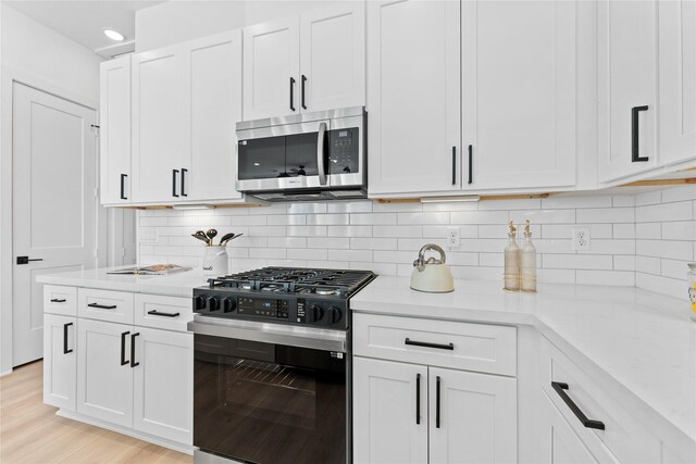3109 Jensen Dr Unit B, Houston, TX 77026 - kitchen with light stone countertops, light hardwood / wood-style floors, decorative backsplash, white cabinets, and appliances with stainless steel finishes