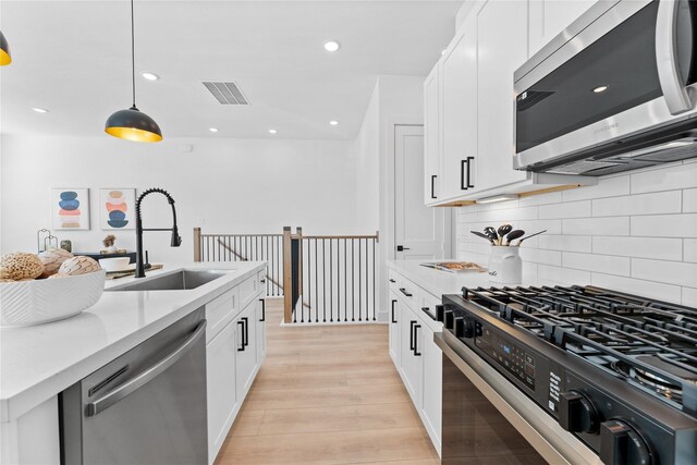 3109 Jensen Dr Unit B, Houston, TX 77026 - kitchen featuring white cabinets, sink, decorative light fixtures, light hardwood / wood-style floors, and stainless steel appliances
