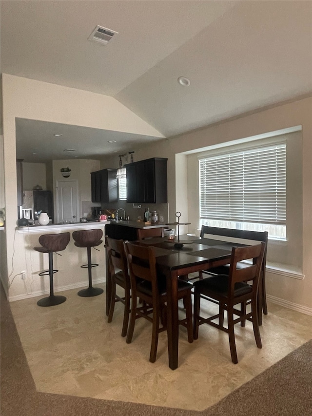 carpeted dining space featuring sink and vaulted ceiling