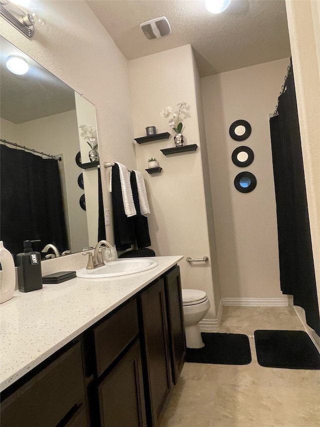 bathroom featuring vanity, toilet, and a textured ceiling