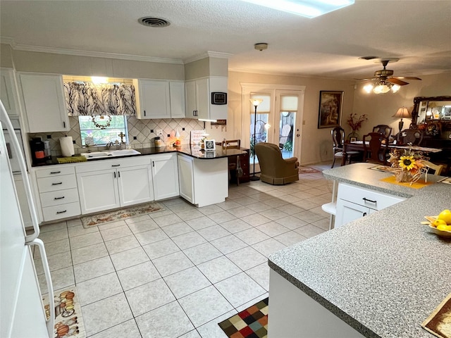 kitchen with white fridge, white cabinetry, tasteful backsplash, and sink