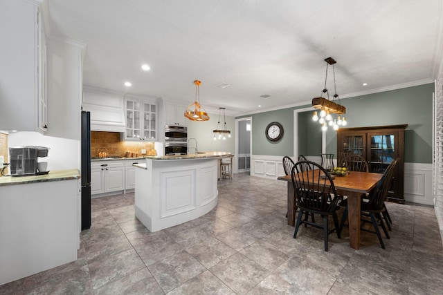 kitchen with a center island, white cabinetry, hanging light fixtures, and ornamental molding