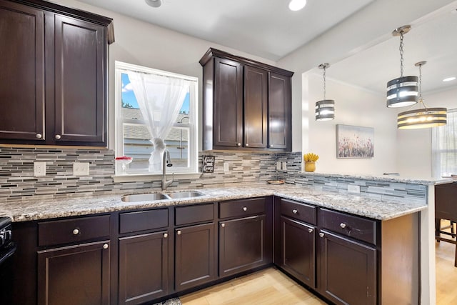 kitchen with sink, kitchen peninsula, hanging light fixtures, and light hardwood / wood-style flooring