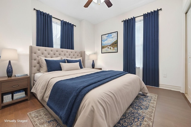 bedroom featuring dark hardwood / wood-style flooring, a closet, multiple windows, and ceiling fan