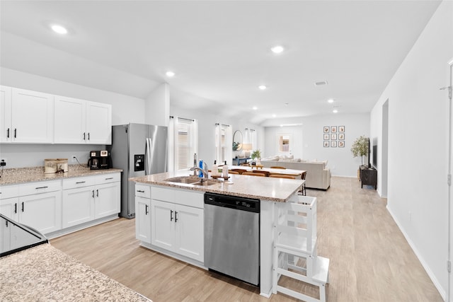 kitchen featuring light stone countertops, appliances with stainless steel finishes, light hardwood / wood-style floors, and white cabinetry