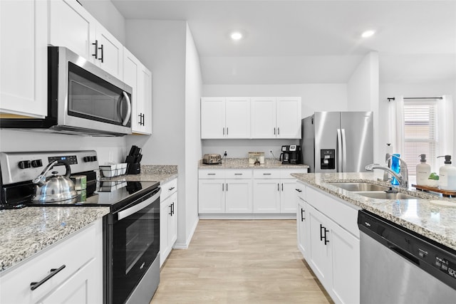 kitchen with sink, light stone countertops, light hardwood / wood-style floors, white cabinetry, and stainless steel appliances