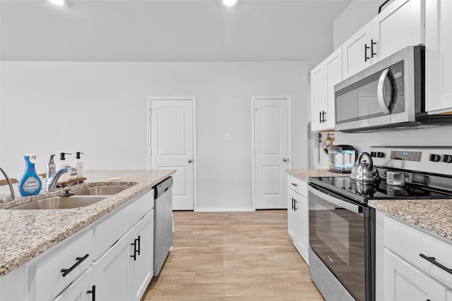 kitchen with appliances with stainless steel finishes, light hardwood / wood-style floors, white cabinetry, and sink