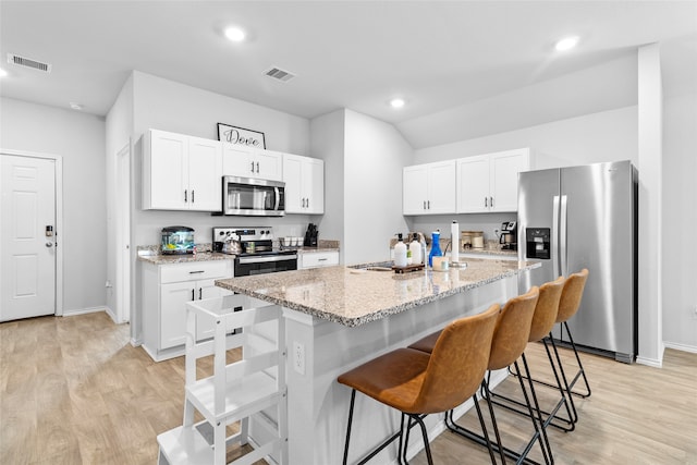 kitchen with a kitchen island with sink, light wood-type flooring, appliances with stainless steel finishes, a kitchen bar, and white cabinetry