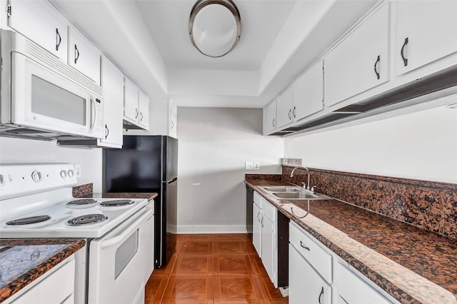 kitchen with white cabinets, dark tile patterned floors, white appliances, and sink