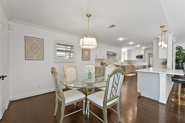 dining room with crown molding, sink, and dark hardwood / wood-style floors