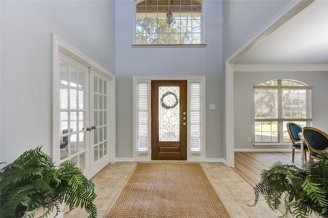 entryway featuring french doors, a wealth of natural light, crown molding, and light tile patterned flooring