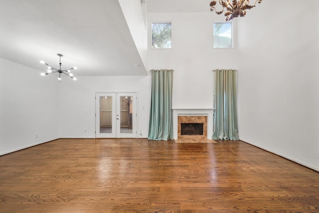2555 Bering Dr Unit 1, Houston, TX 77057 - unfurnished living room with a tile fireplace, a chandelier, a towering ceiling, wood finished floors, and french doors