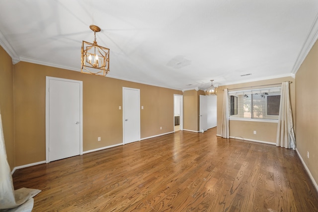 empty room featuring hardwood / wood-style floors, a chandelier, and ornamental molding