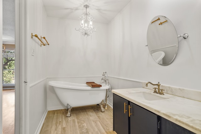 bathroom featuring a tub to relax in, hardwood / wood-style floors, vanity, and an inviting chandelier