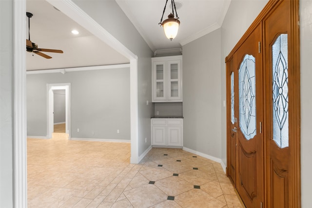 foyer with baseboards, light tile patterned floors, a ceiling fan, and crown molding