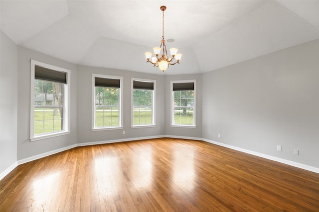 empty room with wood-type flooring, an inviting chandelier, and plenty of natural light