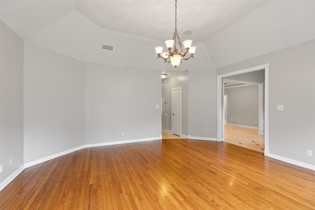 spare room with lofted ceiling, light wood-style floors, visible vents, and baseboards