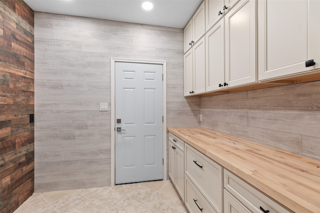 clothes washing area featuring wooden walls and light tile patterned floors