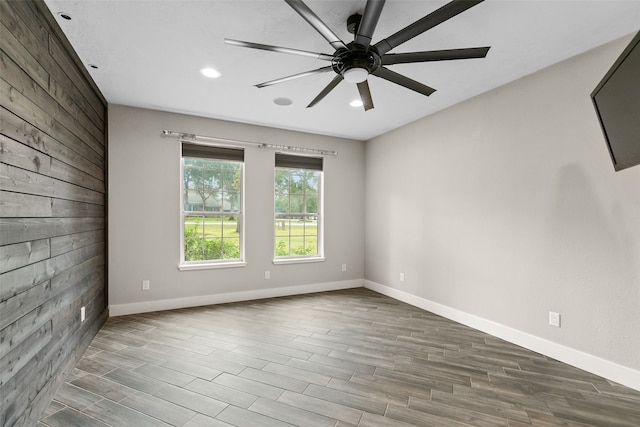 unfurnished room with ceiling fan, wood walls, and hardwood / wood-style flooring