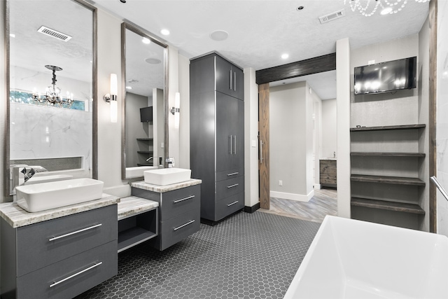 full bathroom featuring two vanities, a freestanding tub, visible vents, and a sink