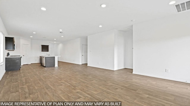 unfurnished living room featuring hardwood / wood-style flooring and sink