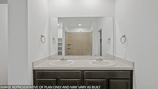 bathroom with a tile shower and vanity