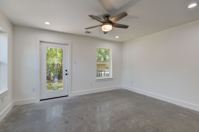 empty room featuring ceiling fan, a wealth of natural light, and concrete floors