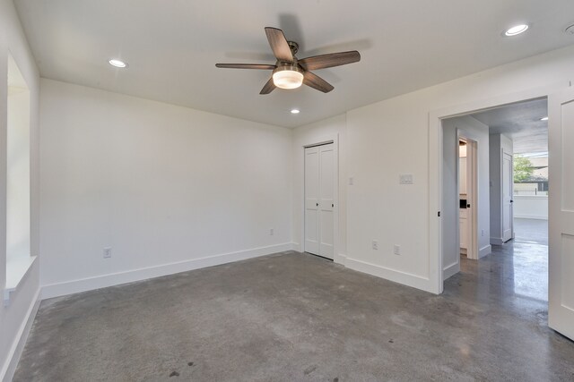 empty room with ceiling fan and concrete flooring