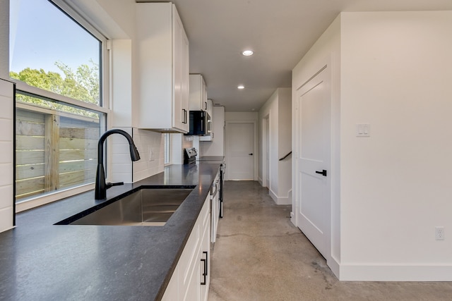 kitchen featuring tasteful backsplash, white cabinetry, sink, and stainless steel appliances