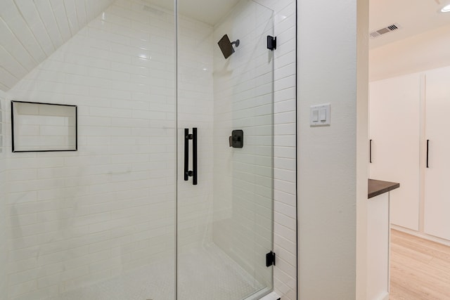 bathroom featuring a shower with door, wood-type flooring, and lofted ceiling