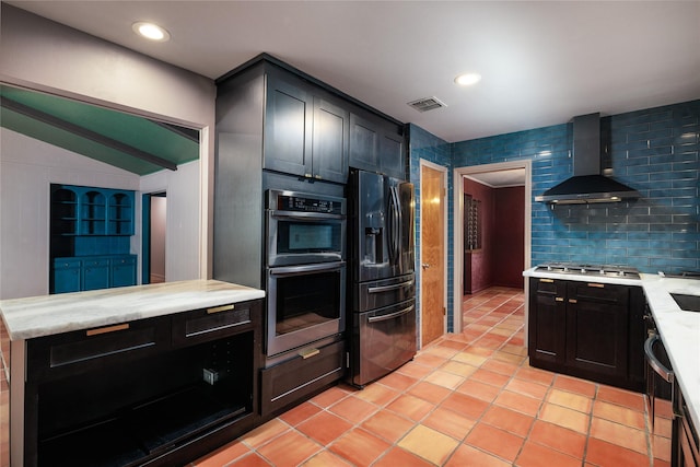 kitchen featuring lofted ceiling, wall chimney exhaust hood, decorative backsplash, light tile patterned floors, and stainless steel appliances