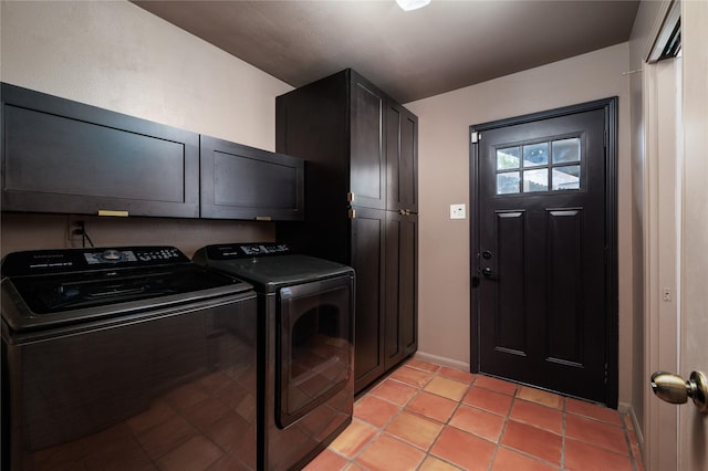 clothes washing area featuring cabinets, light tile patterned floors, and washer and clothes dryer