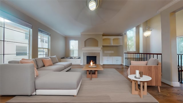 living room featuring hardwood / wood-style flooring, ornamental molding, and a fireplace