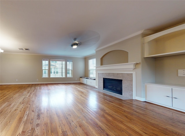 unfurnished living room with crown molding, a fireplace, ceiling fan, and light wood-type flooring