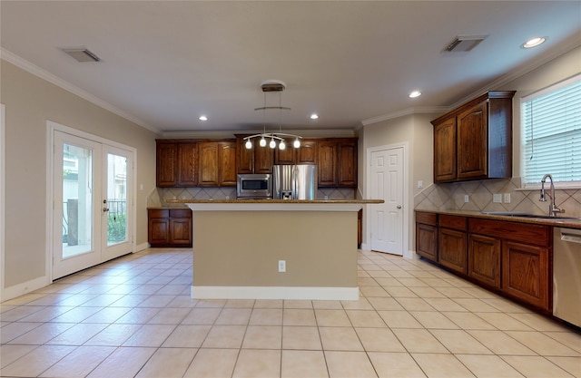 kitchen with pendant lighting, a kitchen island with sink, french doors, sink, and stainless steel appliances